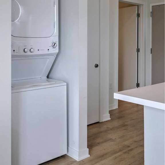 a white washing machine is in a small laundry room.