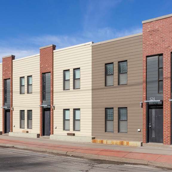 a row of modern buildings with a red brick building on the end.