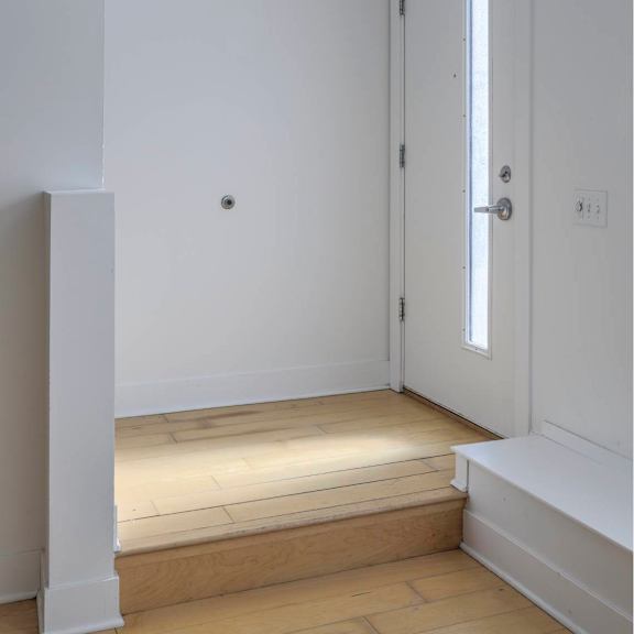 a white door is in a white room with a wooden floor.