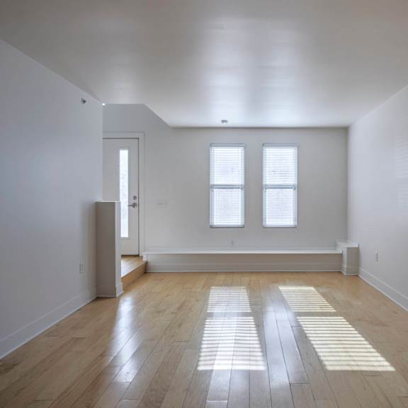 a room with wooden floors and two windows.