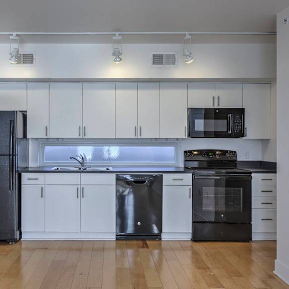 a kitchen with a black refrigerator, black oven, and black microwave.
