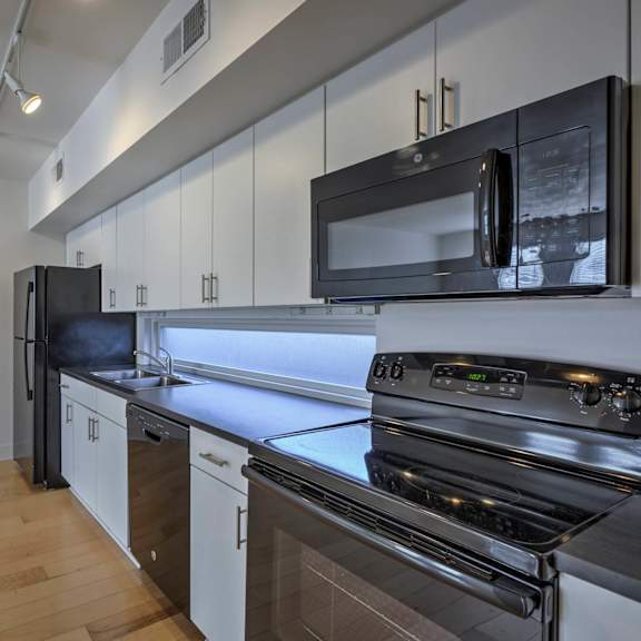 a modern kitchen with black appliances and wooden floors.
