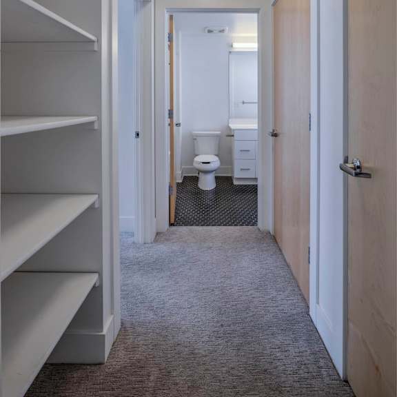 a hallway with a toilet in the distance and a door on the right.