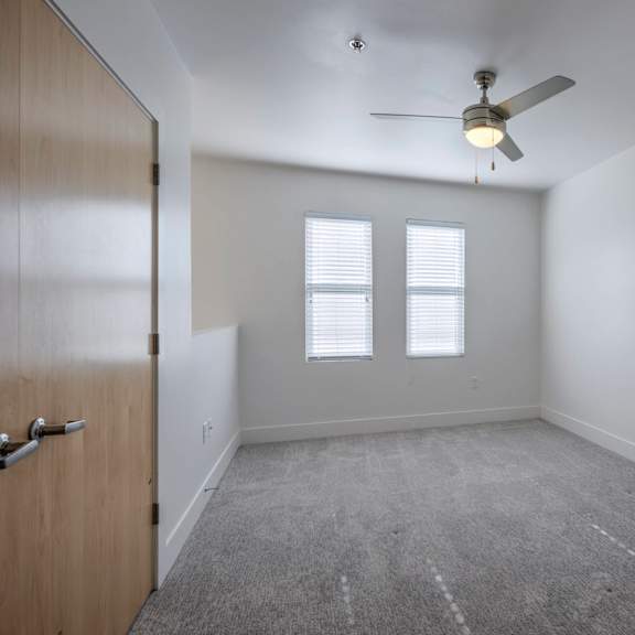 a room with a ceiling fan and carpeted floor.