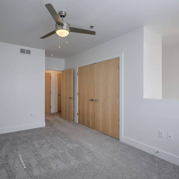 a room with a ceiling fan and carpeted floor.