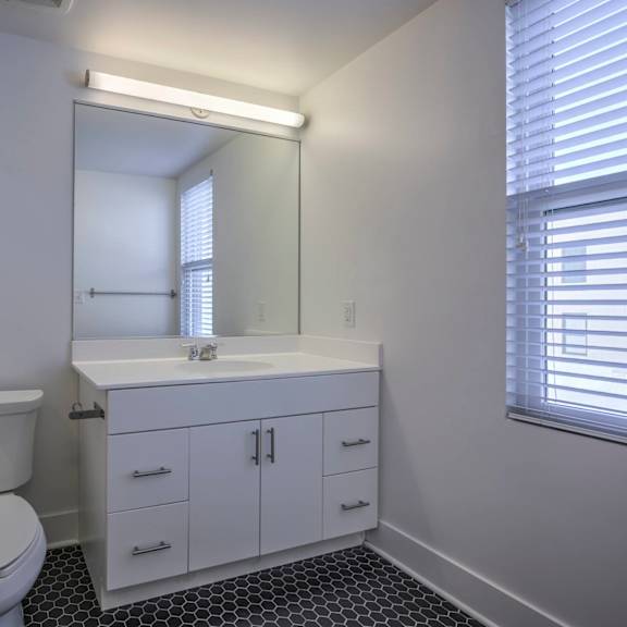 a white bathroom with a toilet, sink, and mirror.