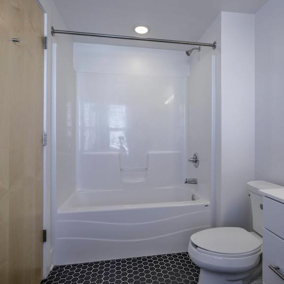 a white toilet sits next to a bathtub in a bathroom.