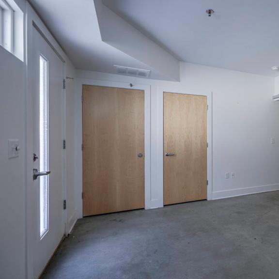 three wooden doors are closed in a white room.