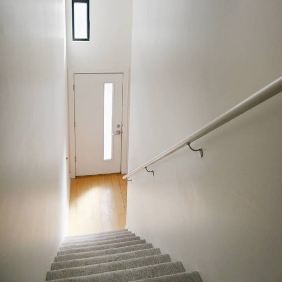 a staircase with a carpeted runner and a metal handrail.