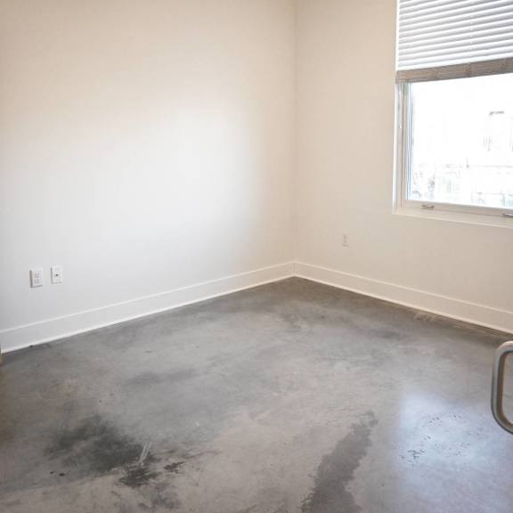 a room with a concrete floor and a window with blinds.