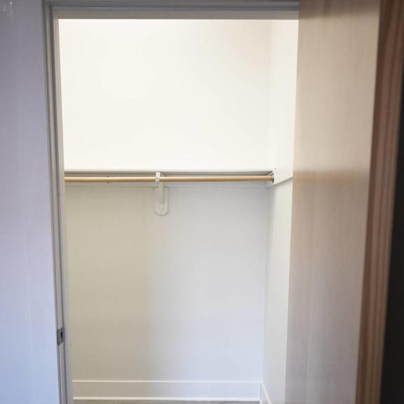 a white door with a silver handle is open to a room with a white wall and a brown door.
