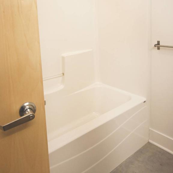 a white bathtub in a bathroom with a wooden door.