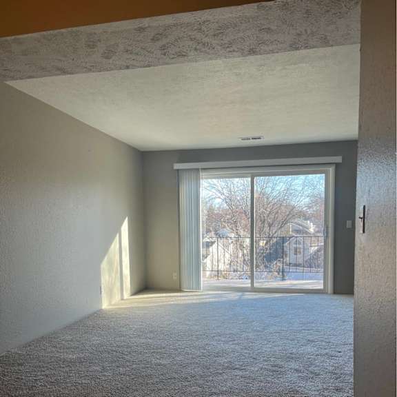 a room with a carpeted floor and a sliding glass door leading outside.