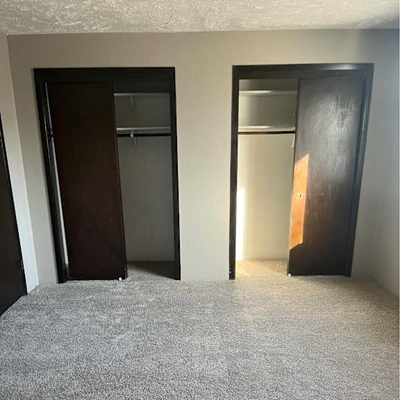 a carpeted room with two doors.