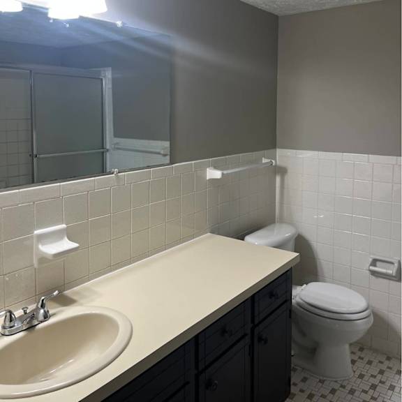 a bathroom with a toilet, sink, and mirror.