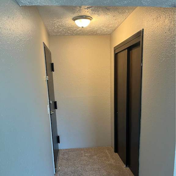 a hallway with a carpeted floor and a door on the right.