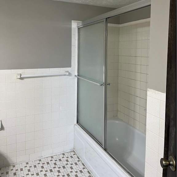 a white tiled bathroom with a glass shower door.