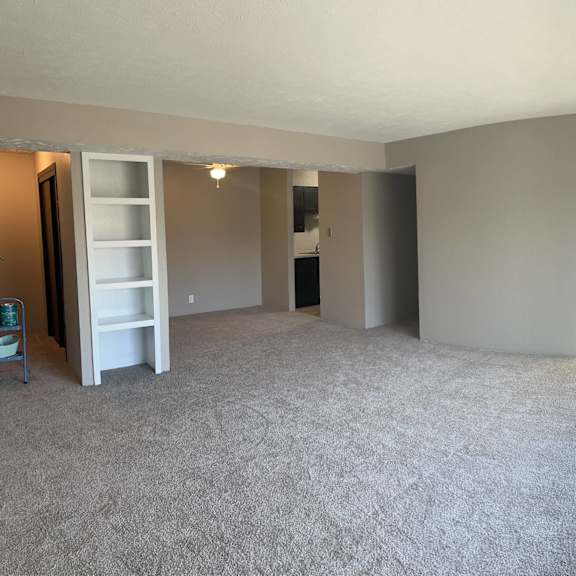 a large, empty room with a carpeted floor and a window letting in natural light.