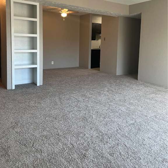 a room with a grey carpet and a white shelf unit.