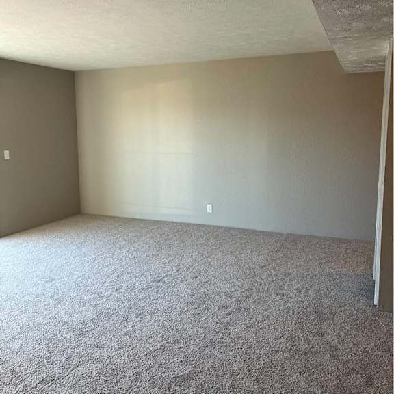 a room with a carpeted floor and a light switch on the wall.