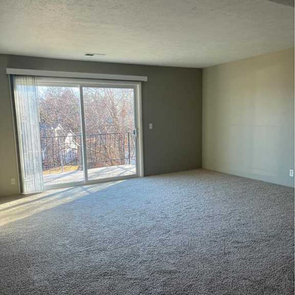 a room with a carpeted floor and a sliding glass door.