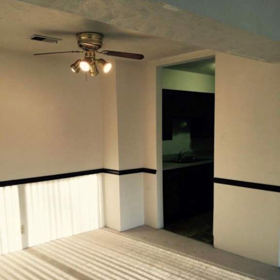 a room with a ceiling fan and sunlight coming through the window.