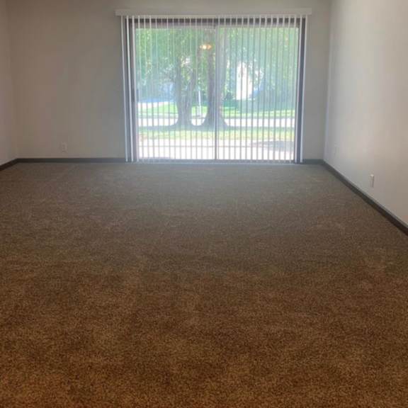 a room with a carpeted floor and a window with blinds.