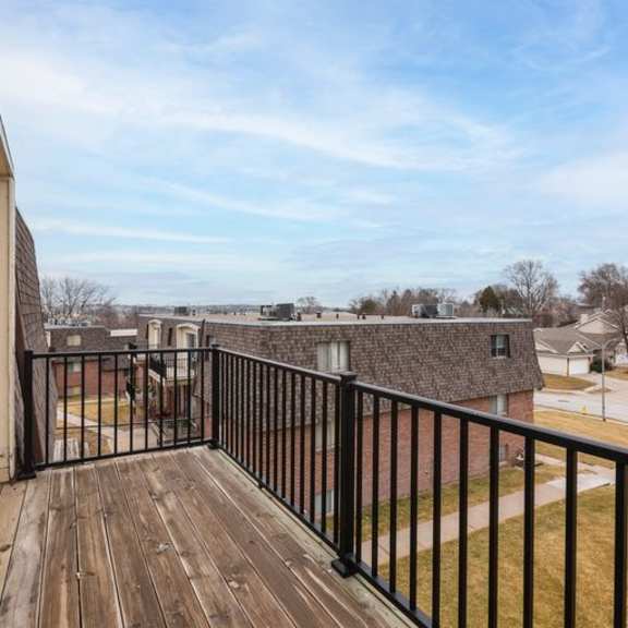 a balcony with a black railing overlooks a residential area.