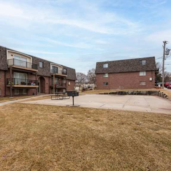a grassy area in front of apartment buildings with a picnic table.