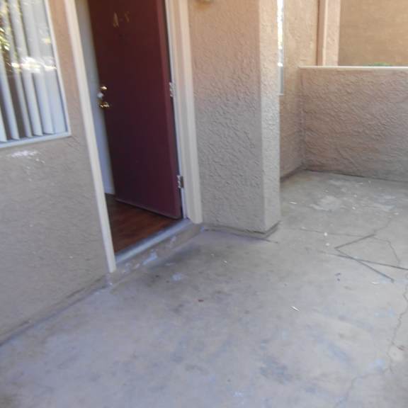 a concrete patio with a red door and white walls.