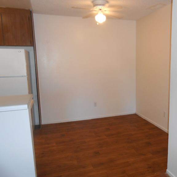 a room with a wooden floor and a white wall with a light switch.