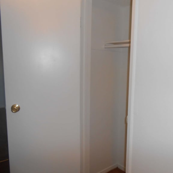 a white door with a gold handle is open to a white hallway.