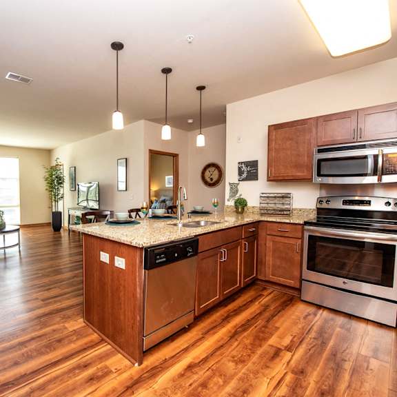 a kitchen and living room with wood flooring and stainless steel appliances