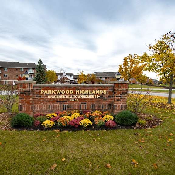 a brick sign that says parkwood highlands apartments in front of a building.