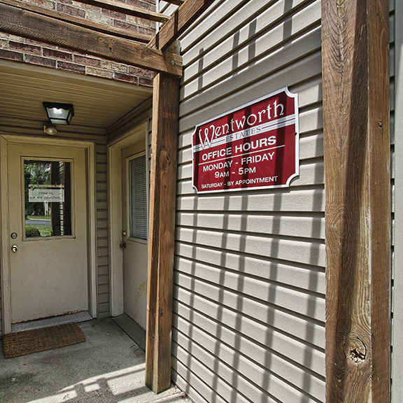 the front door of a brick building with a red and white sign at at wentworth estates apartments, florence, ky, 41042