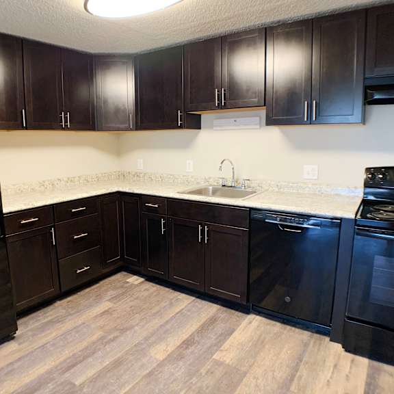 a kitchen with dark wood cabinets and a black refrigerator