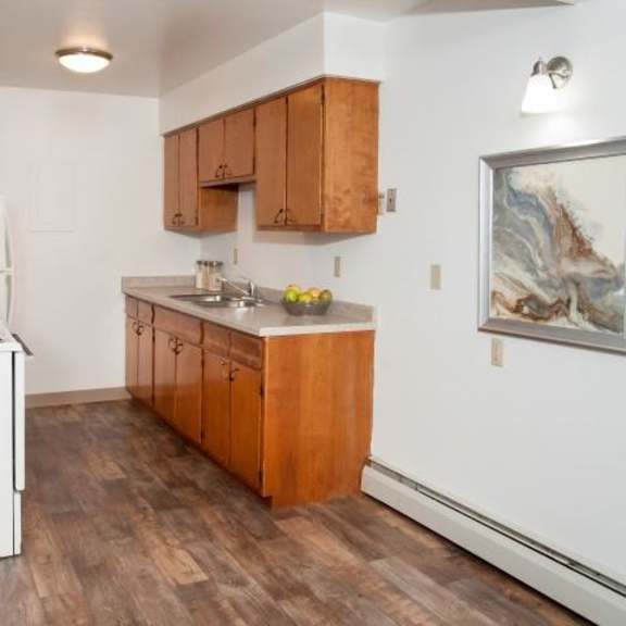 bright kitchen at 8920 wentworth apartmetns with white walls and dark wood floors