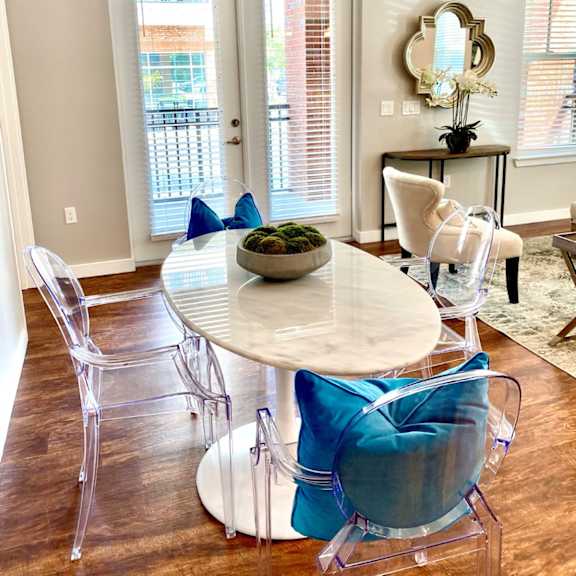 a dining room with hardwood-style flooring with access to a living room and near a double door entrance to a private balcony.