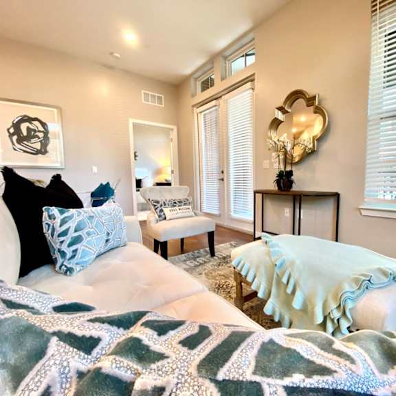 a living room with a window, hardwood-style flooring, and near double doors to a private balcony.