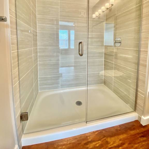 a large walk-in shower with glass doors and and modern floor-to-ceiling tile walls.