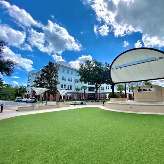 an outdoor stage at the tioga town center with astro turf and trees near the flats at tioga town center apartments.