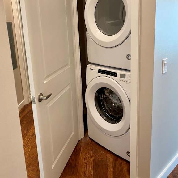 a closet in a hallway with a modern stacked washer and dryer combination.