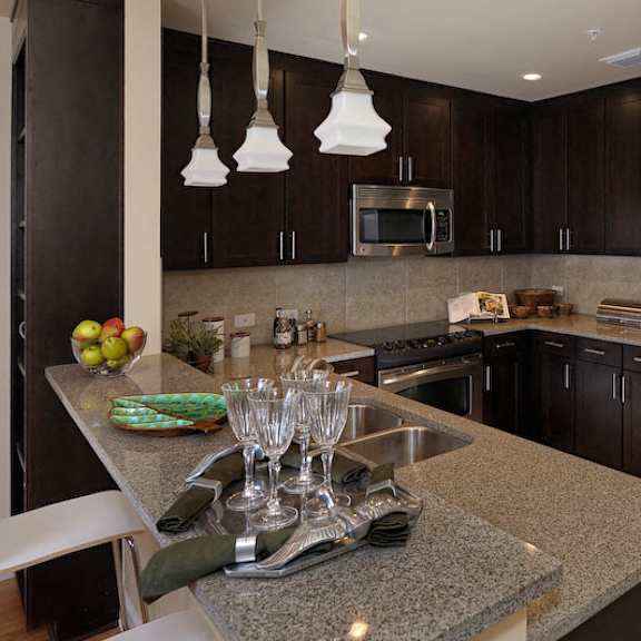 an updated kitchen with stainless steel appliances, granite countertops, recessed lighting, modern pendant lights, and a double-basin sink.