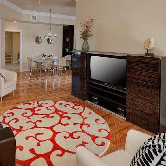 a staged living room with hardwood-style flooring and double door access to a private balcony near a kitchen.