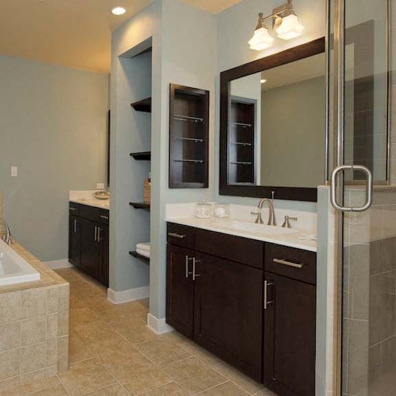 a large bathroom with a bathtub, a walk-in shower, and 2 separate vanity sinks divided by built-in shelving.