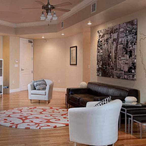 a spacious living room with a ceiling inlay, a ceiling fan, recessed lighting, hardwood style flooring, and access to the front door.