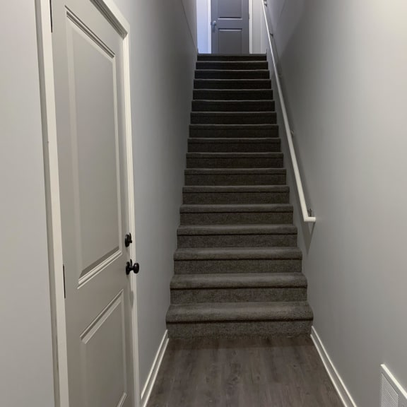 Thumbnail 15 of 21 A staircase with a white door on the left side.