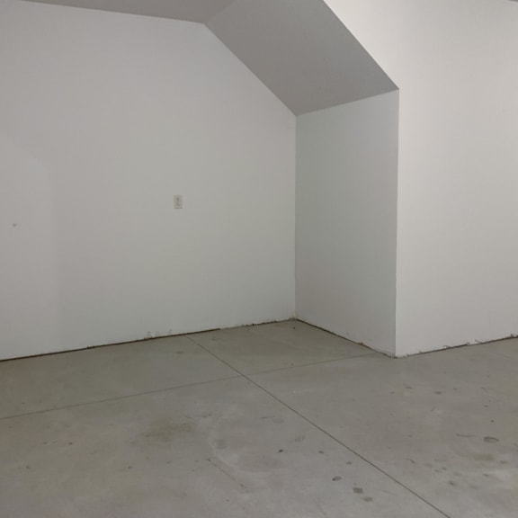 Thumbnail 17 of 21 A white room with a concrete floor and a white wall.