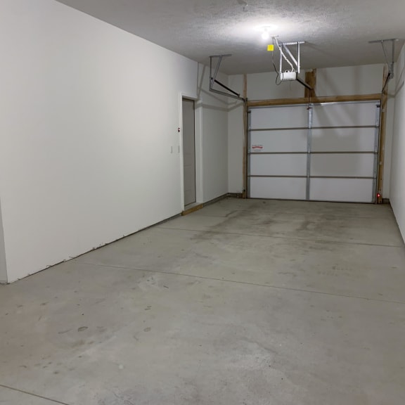 Thumbnail 16 of 21 A large empty garage with a white door and a white ceiling light.