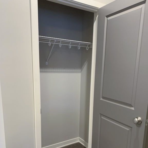 Thumbnail 6 of 21 A white closet with a grey door and a grey shelf.